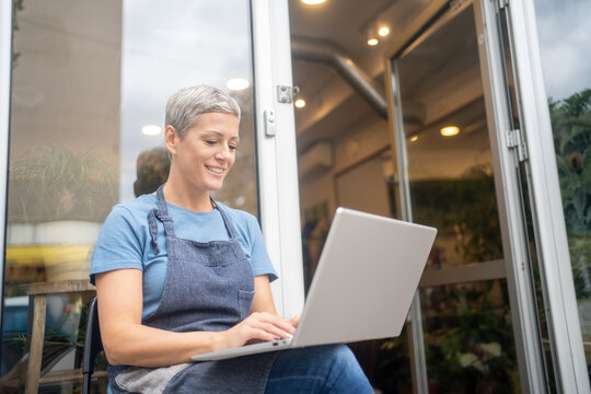 Female florist checking online orders laptop small business