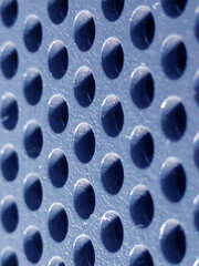 Obraz premium Close-up of shiny perforated metal surface with blurred background and patterned holes