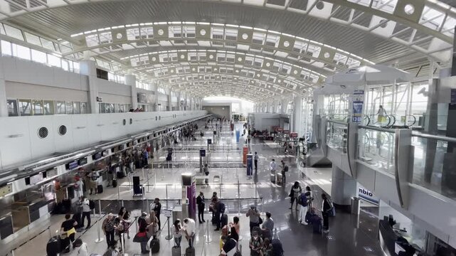 Spacious modern airport terminal interior with travelers at check-in counters bright architecture and high ceiling