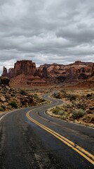 Fototapeta premium Winding road through monument valley a dramatic desert landscape under cloudy skies