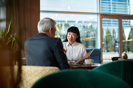 Two business professionals reviewing documents in coffee shop