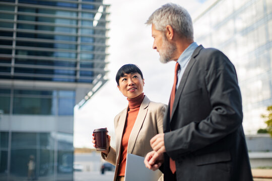 Business colleagues talking outside modern office