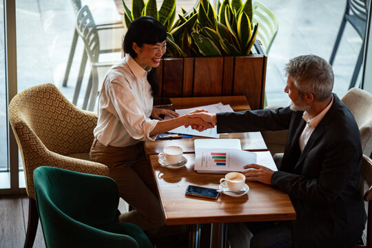 Business colleagues shaking hands at cafe meeting