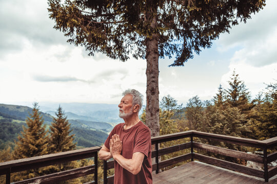 Senior man meditating on mountain deck in forest