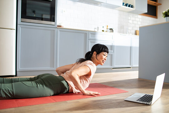 Woman doing online yoga workout in home kitchen
