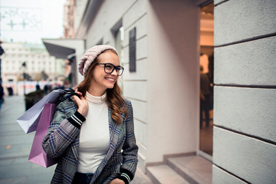 Smiling woman with shopping bags walking in city street