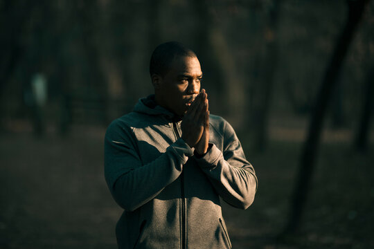 Man in hoodie warming hands outdoors in park