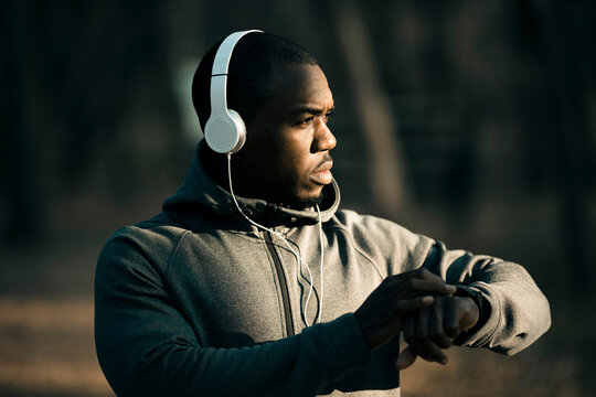 Man checking smartwatch while jogging outdoors with headphones