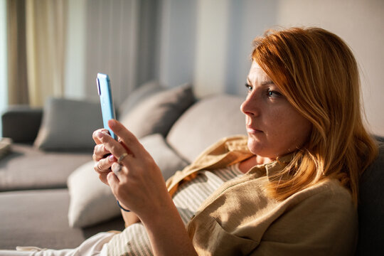 Woman using smartphone on couch at home