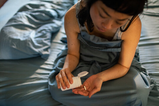 Woman taking medication in bed at home