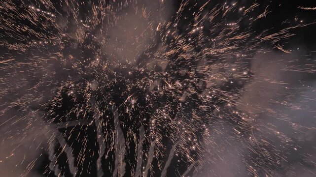 Time-lapse shot of series of colorful fireworks display lighting up night sky over during festival or celebration, with bright sparkling white and red rockets bursting beautifully