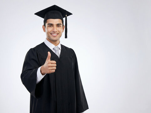 handsome indian male graduate giving thumbs up in graduation gown representing academic success career achievement and education excellence concept