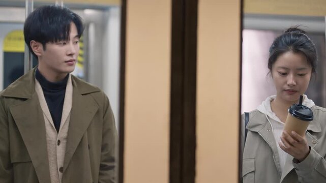 Young asian man and woman having an awkward conversation while commuting on public transport together
