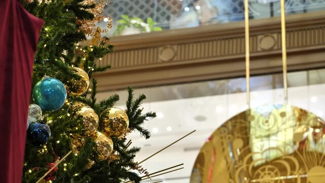 A decorated Christmas tree against the backdrop of a swinging clock pendulum.