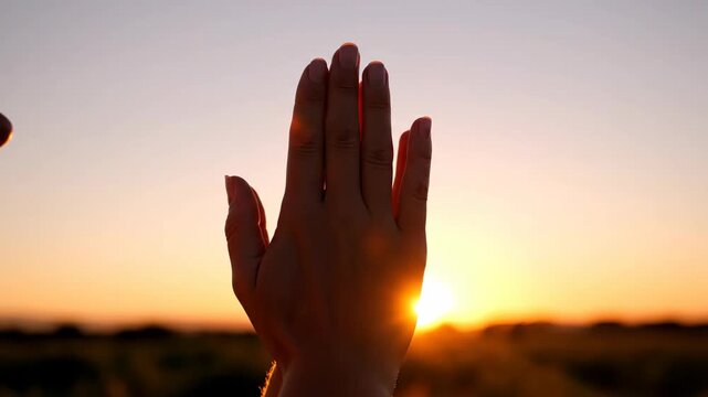 Woman hand blocking sun ray prayer gesture at sunset. Religion symbol meditation and spiritual worship on horizon.