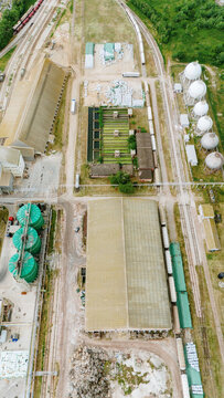 Aerial view of an industrial complex featuring large warehouses, spherical storage tanks, and railway tracks with freight cars Sabac, Vojvodina, Serbia.