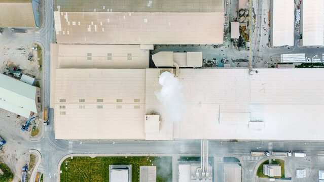 Aerial view of an industrial factory with white smoke rising from a chimney and surrounding warehouses in Sabac, Vojvodina, Serbia.