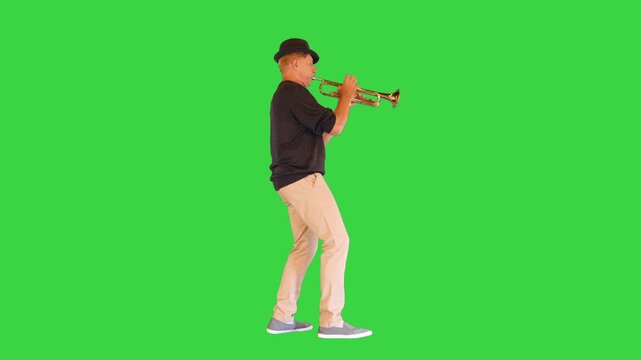 A senior man in black hat plays the trumpet on a Green Screen, Chroma Key.