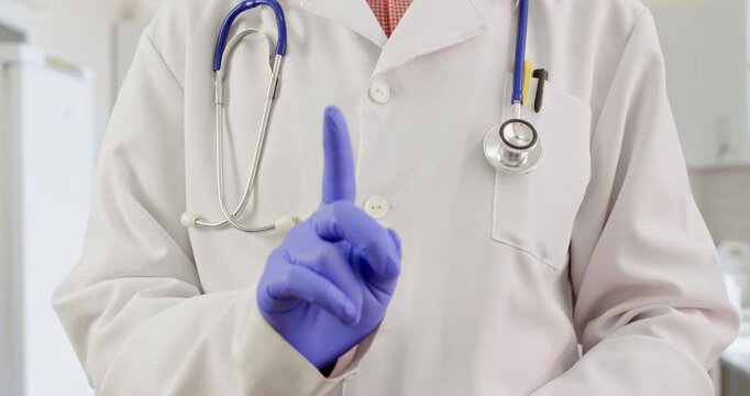 A doctor in a white coat warns a patient with a hand gesture, moving the index finger of his hand in front of him.