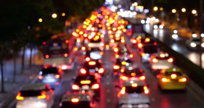 Telephoto shot of heavy traffic Bangkok at night, shot out-of-focus to create vibrant bokeh effect of glowing red brake lights stretching in diminishing perspective.