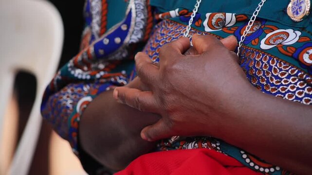 Hands of an African woman wearing green and red dresses