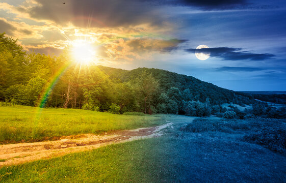 day meet night in beautiful countryside. epic view landscape in mountains on summer solstice. sun and moon in harmony over trail through the grassy field near forested rolling hills. rural scenery