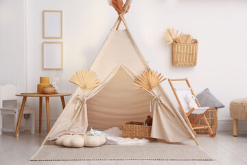 Stylish wigwam with dry leaves in child's room © New Africa