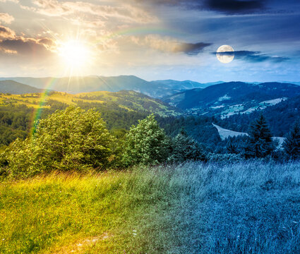day meet night. agricultural field on hillside in mountains. sun and moon over carpathian mountain landscape on summer solstice. countryside view of alpine fields and rolling hills. epic sky