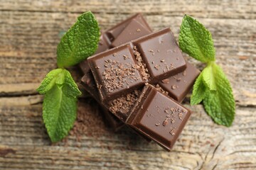 Pieces of yummy chocolate and mint leaves on wooden table, closeup © New Africa