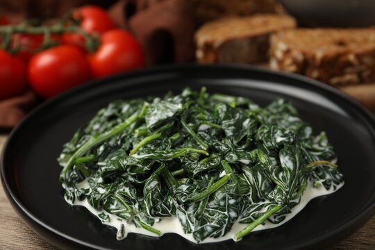 Delicious creamed spinach served on wooden table, closeup