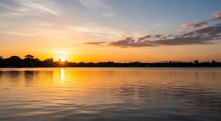 Obraz premium Vibrant Sunset Over Calm Water with Distant Tree Line