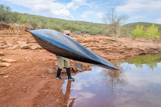 senior paddler is launching his decked touring canoe on shore of Horsetooth Reservoir - early spring scenery of Colorado foothills