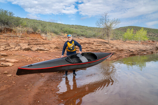 senior paddler is launching his decked touring canoe on shore of Horsetooth Reservoir - early spring scenery of Colorado foothills