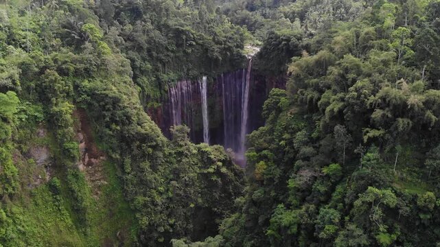 Drone Flying Above Forest Towards Tumpak Sewu Waterfall Panning Down to Reveal Falls, Java, Indonesia