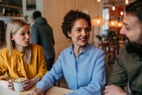 Friends talking and smiling over coffee in cafe