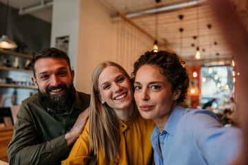 Fototapeta premium Friends taking happy group selfie at cafe
