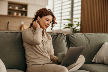 Fototapeta premium Woman working remotely at home wearing pajamas with laptop