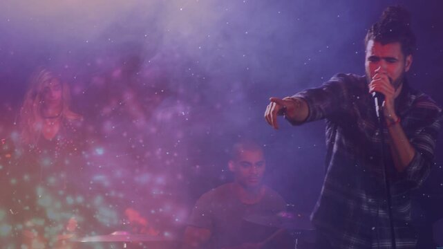 Lead vocalist pointing, moving center and gripping mic in concert, engaging crowd amid sparkles