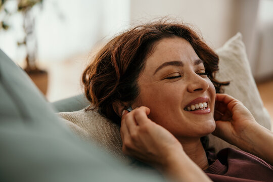 Woman enjoying music relaxing with earbuds in home