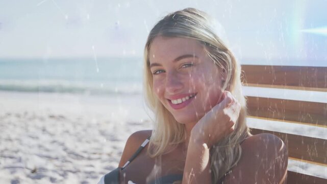 Adult female sitting beach chair right hand tucking hair to jaw, film overlays giving retro fashion