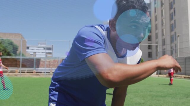 Man on sports pitch gasping, raising arm shielding eyes from sun while overlays obscuring player