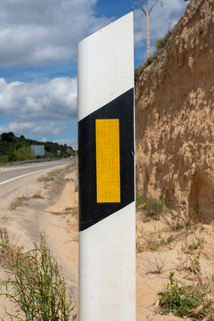 Detalle de hito de arista reflectante en el margen de una carretera secundaria.