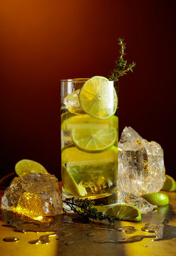 Cold refreshing drink with ice and lime in tall glass with water condensation drops.