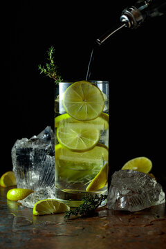 Cold refreshing drink with ice and lime in tall glass with water condensation drops.