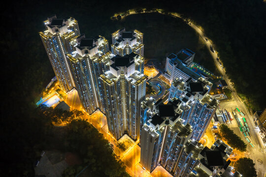 Stunning aerial night view of glowing high rise residential towers in Hong Kong showcases dense urban living and modern architectural scale.