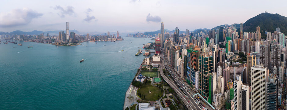 High-angle view of the bustling skyline and coastal highway in Hong Kong during the day, showcasing the city architectural scale and urban density.