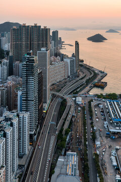 High-angle view of the bustling skyline and coastal highway in Hong Kong during the day, showcasing the city architectural scale and urban density.