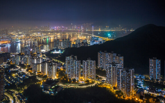 Modern skyscrapers and a busy container port glow under the night sky in Hong Kong, showcasing the city status as a global trade and finance hub.