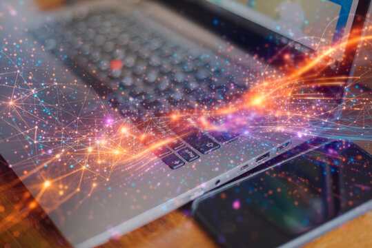 High angle view of laptop and smartphone with glowing digital data streams and network connection for 5G technology and futuristic computing concept