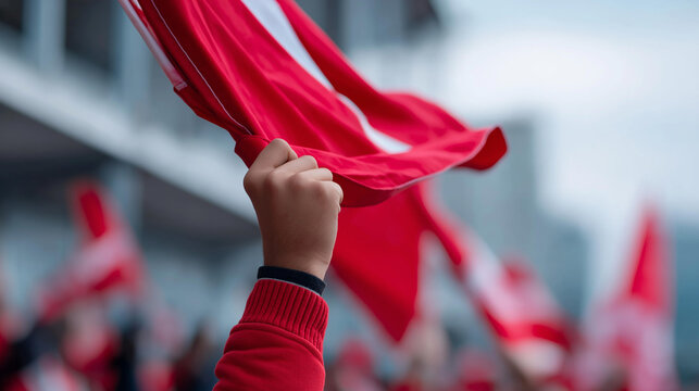 Close-up of a football fan's hands gripping a red team flag in wind at a match, passionate supporter concept, flag waving detail, fan identity expression, defocused background,